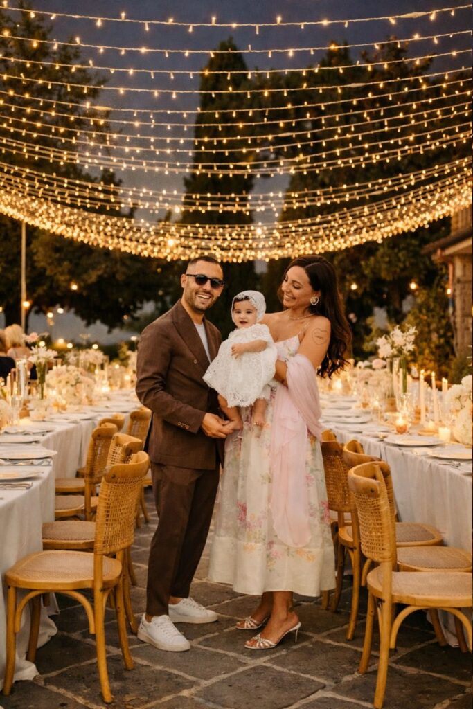 Famiglia durante ricevimento serale sotto luci vintage a cascata con tavoli imperiali allestiti all’aperto