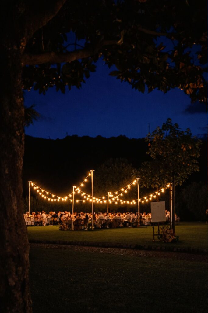 allestimento vintage per matrimonio all’aperto con lampade sospese in fibra naturale e illuminazione serale calda