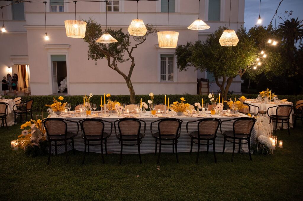 Tavolo imperiale per matrimonio all’aperto con lampade sospese in fibra naturale e illuminazione serale calda